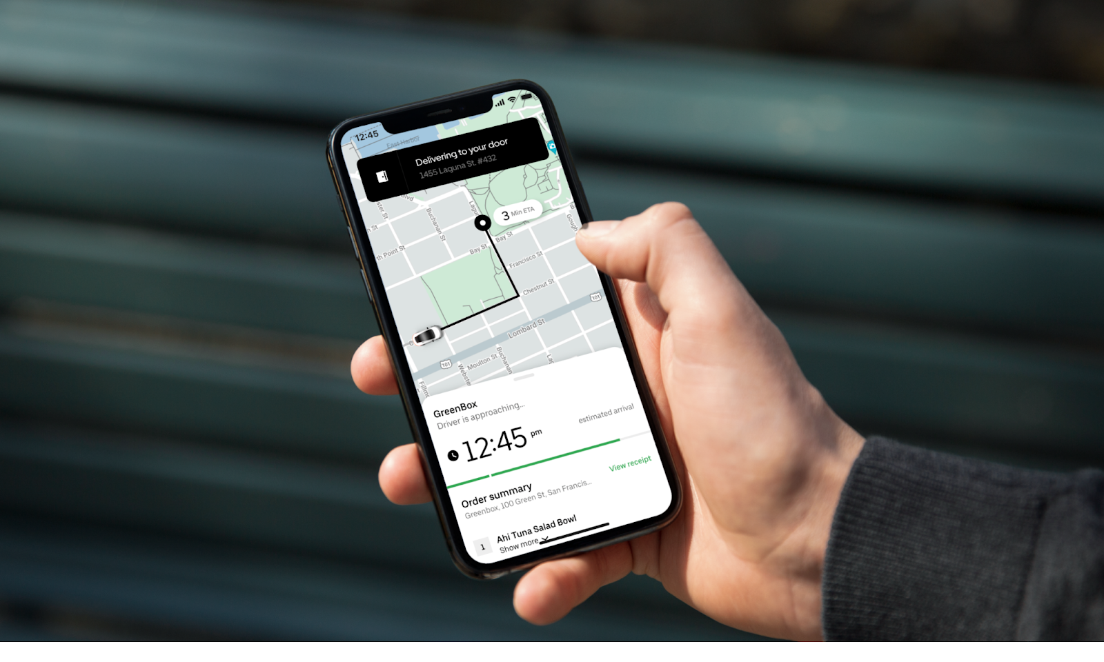 Hand holding a phone with an Uber app open, showing a screen requesting a ride