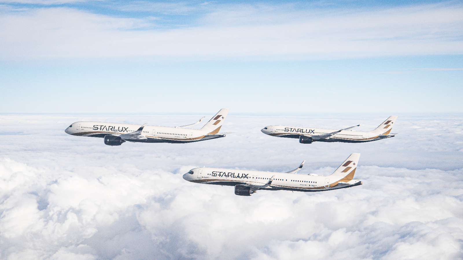 Three STARLUX Airlines aircraft fly in formation above the clouds, with the lead plane slightly ahead and lower than the others under a clear sky.