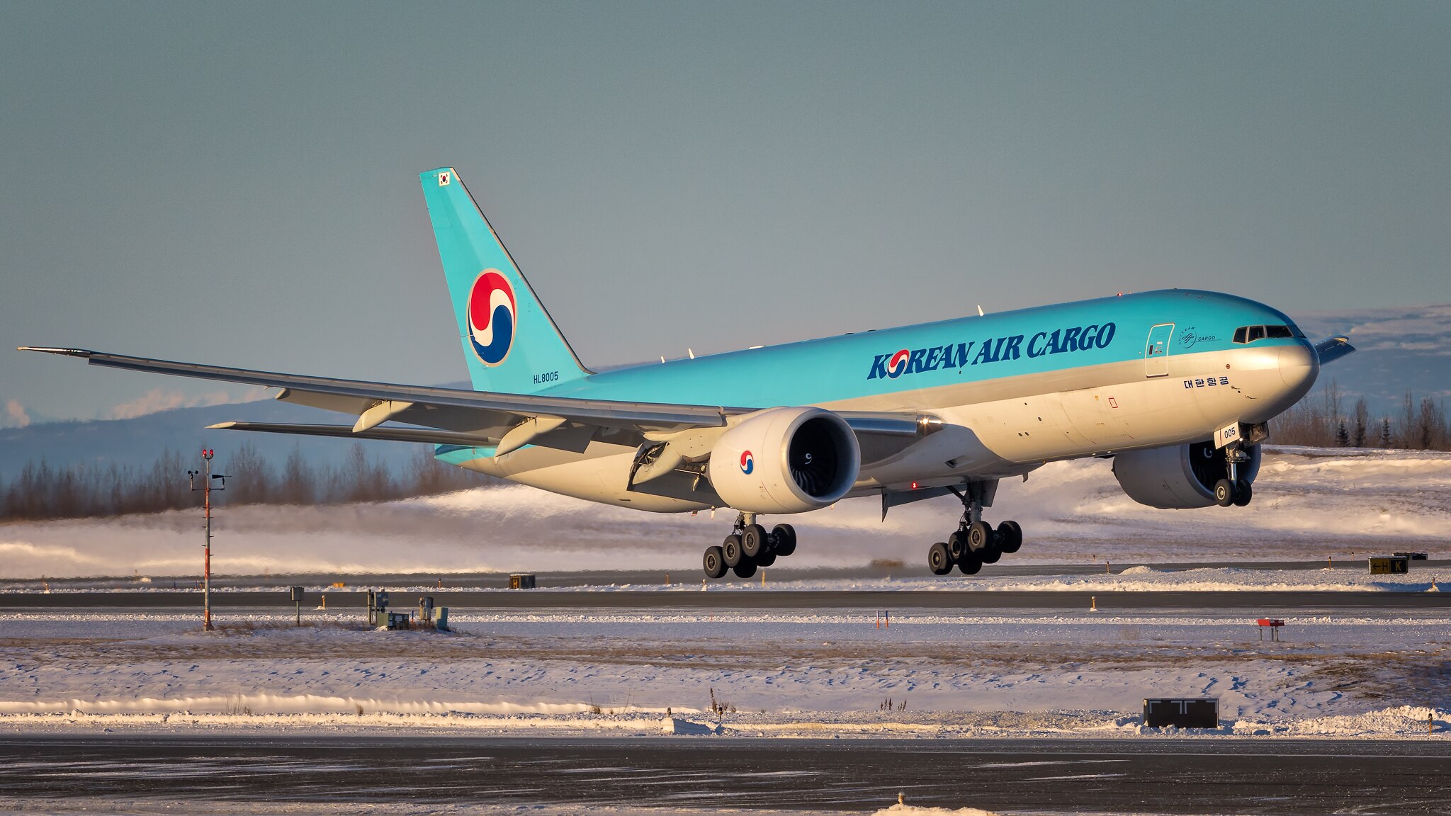 A Korean Air cargo plane taking off in the snow.
