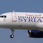 The nose of a Syrian Air A320 aircraft with landing gear out.