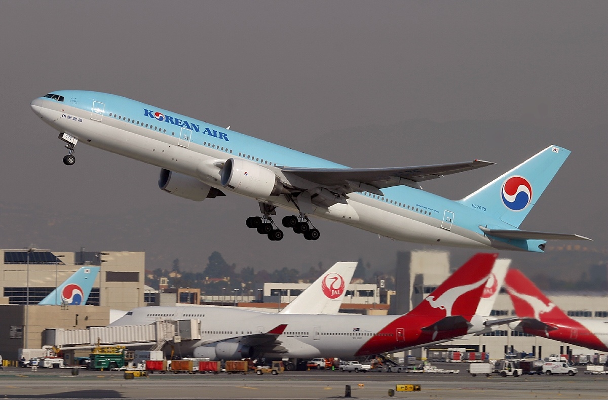A Korean Air Boeing 777 taking off with planes from other airlines in the backgrounds