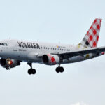 A Volotea aircraft with a plaid design on its tail and landing gear deployed.
