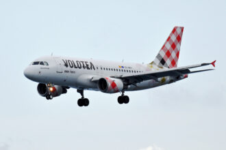 A Volotea aircraft with a plaid design on its tail and landing gear deployed.