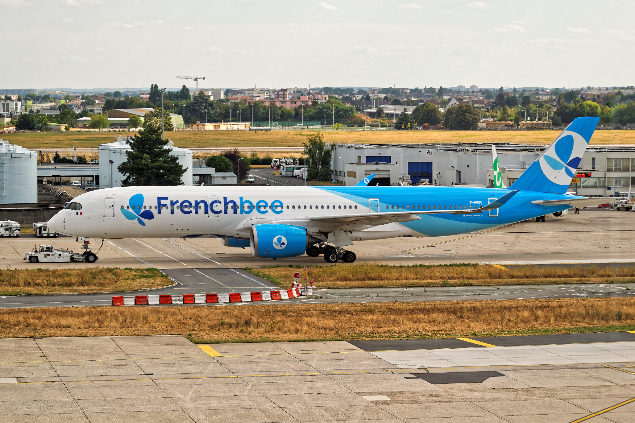 A blue and white French bee aircraft landing at the airport.