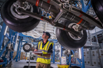 Engineer inspects Airbus landing gear system at Filton site. Image illustrating Airbus UK strike 2025 pay dispute.
