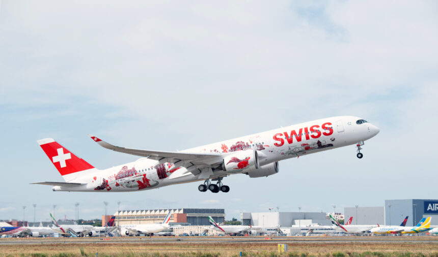 A Swiss International Air Lines aircraft, adorned with red and white livery featuring Swiss cultural symbols and landmarks, takes off from an airport. The plane's tail displays a large white cross on a red background, representing the Swiss flag. Several other airplanes and airport buildings are visible in the background under a partly cloudy sky.