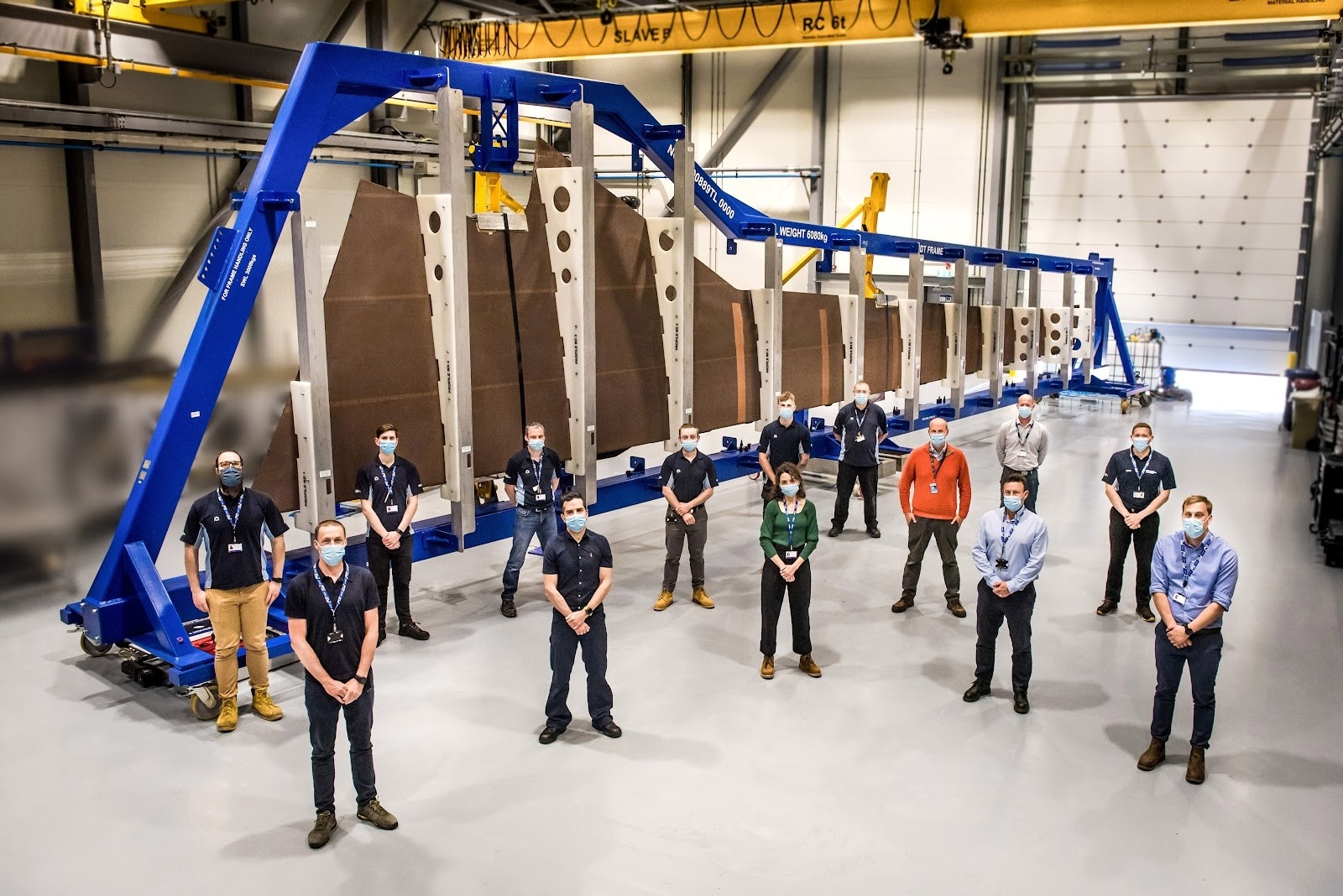 Airbus UK workers at Broughton stand in front of a composite A350 wing cover.