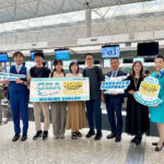 A group of people standing in an airport terminal holding signs celebrating Greater Bay Airlines' milestone of 2 million passengers. The signs read "GBA 2 Million Reasons To Be Grateful".