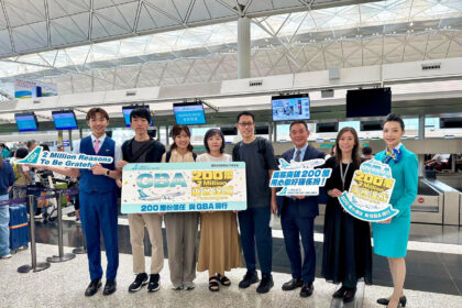 A group of people standing in an airport terminal holding signs celebrating Greater Bay Airlines' milestone of 2 million passengers. The signs read "GBA 2 Million Reasons To Be Grateful".