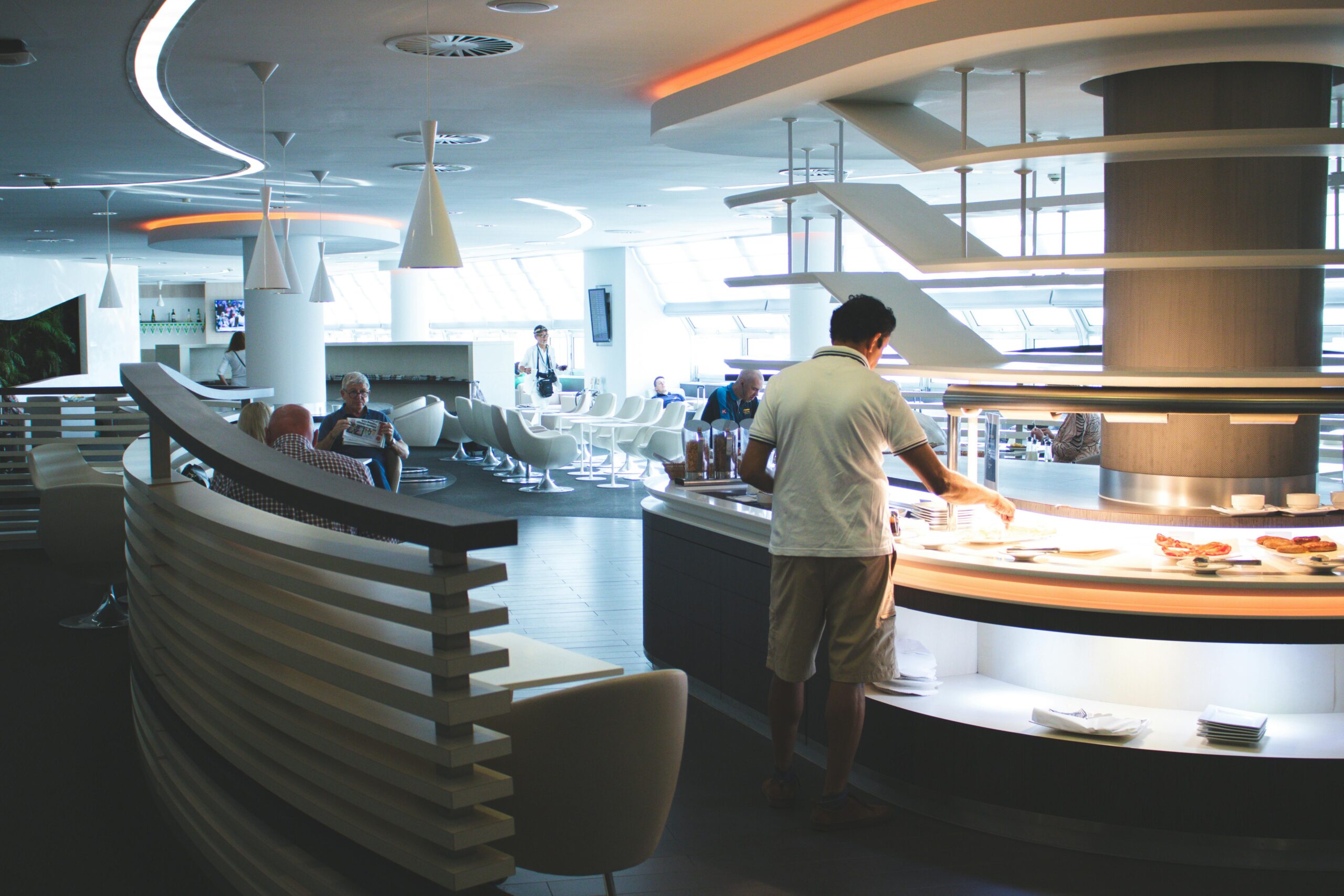 A man in an airport lounge picking food from the buffet