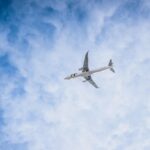 Airplane cruising above the clouds on a clear day, framed against a bright blue sky
