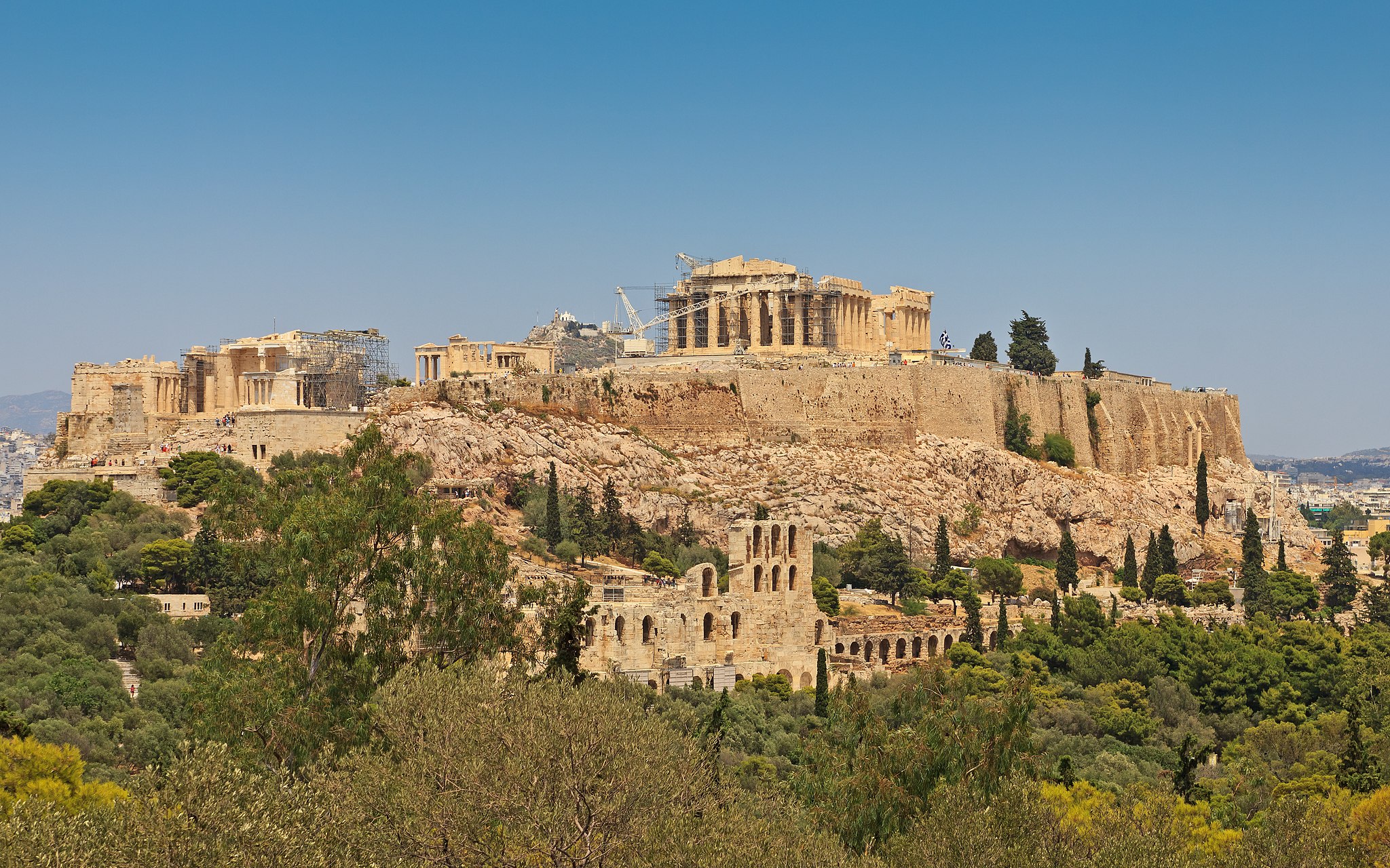 A view of Athens from Acropolis Hill, where one can see the Parthenon and many ancient buildings with the city of Athens surrounding it.