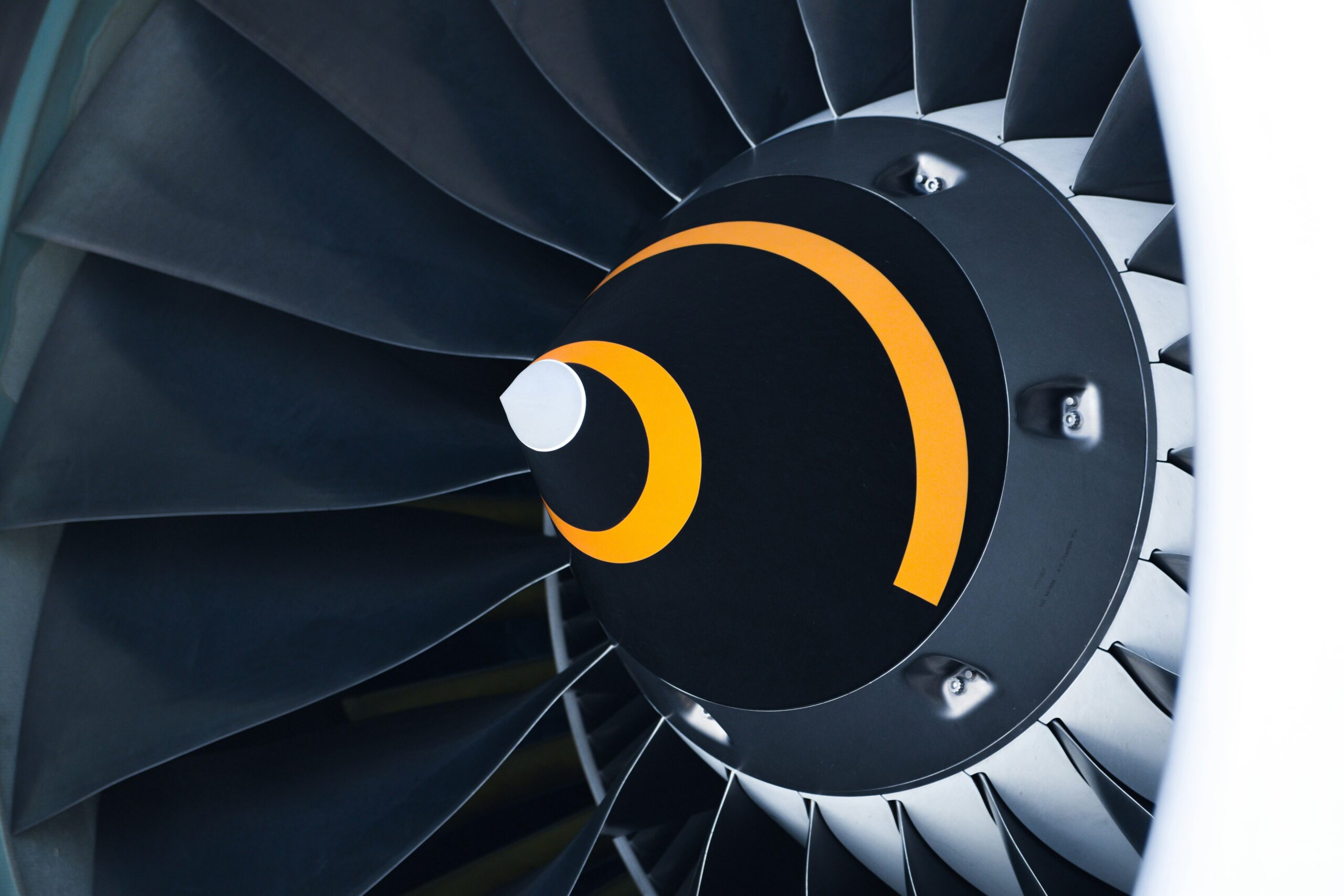 Close-up view of the front section of a jet engine turbine, showcasing the fan blades and the central spinner cone with a distinctive yellow swirl pattern.