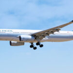 A blue and white Cathay Pacific plane coming in for landing.
