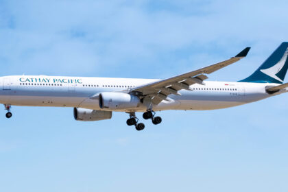 A blue and white Cathay Pacific plane coming in for landing.