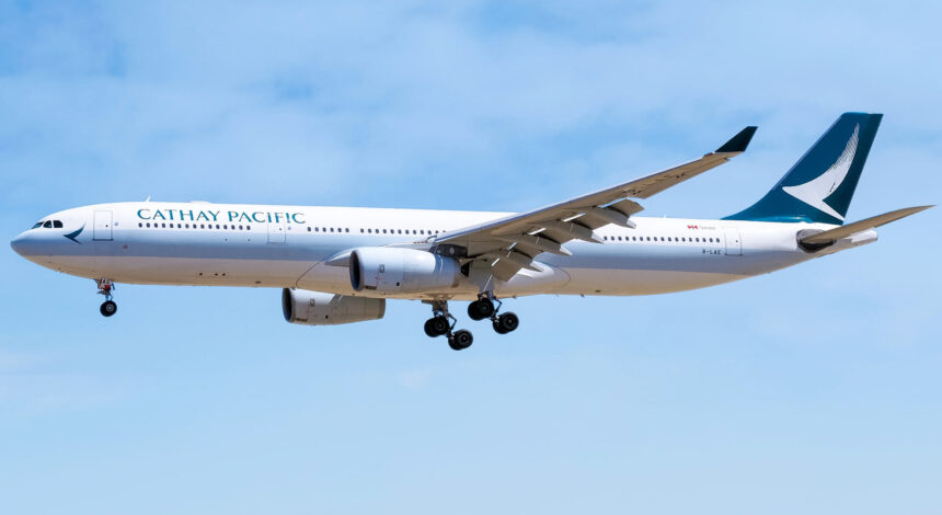 A blue and white Cathay Pacific plane coming in for landing.
