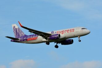 A white HK Express plane with purple and orange accents comes in for landing.