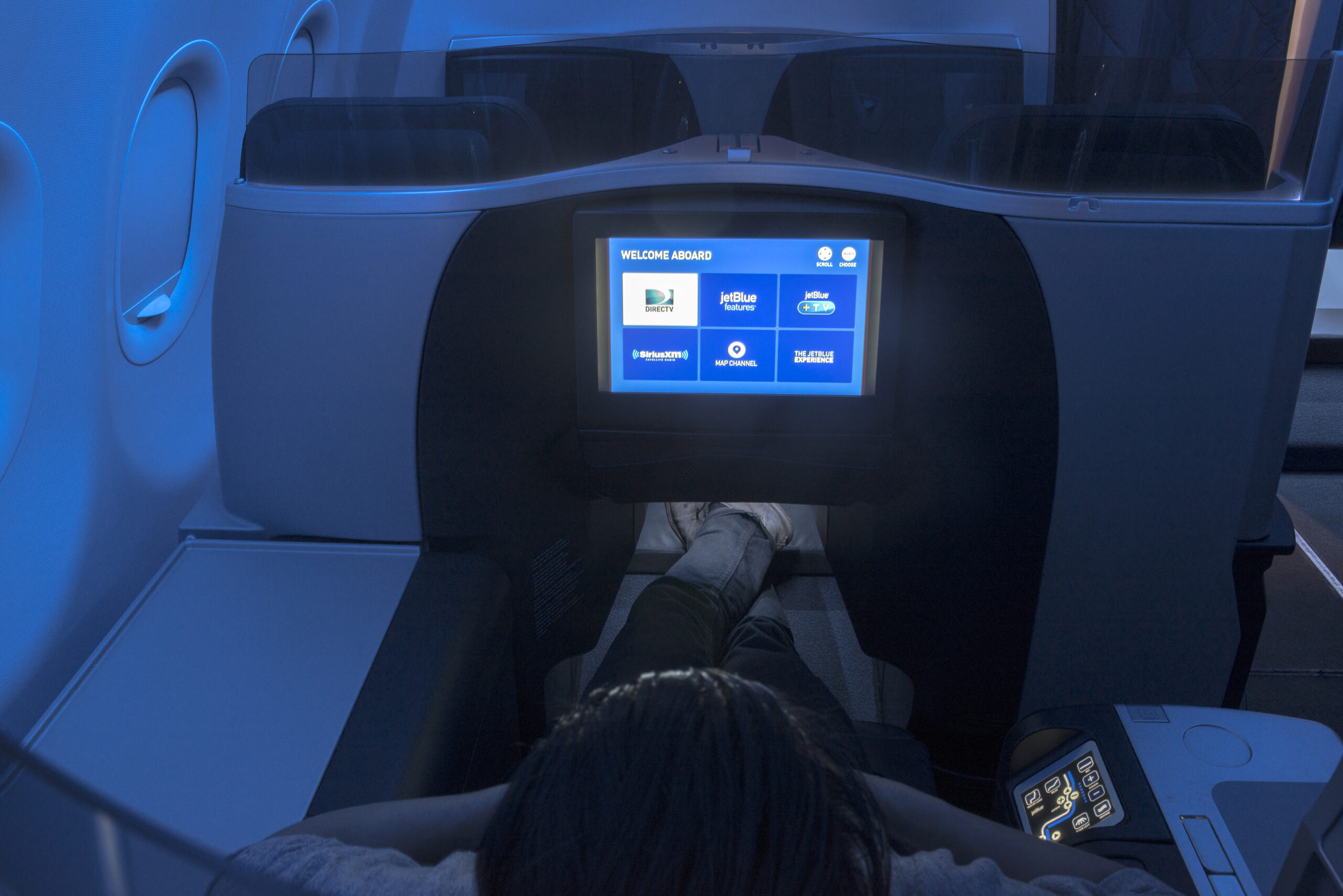 Passenger in JetBlue Mint cabin using seatback screen. Jetblue features include JetBlue free Wi-Fi and future satellite internet upgrades.