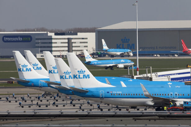 Six KLM blue and white planes are in a line on the tarmac with their tails as the centre of the image.