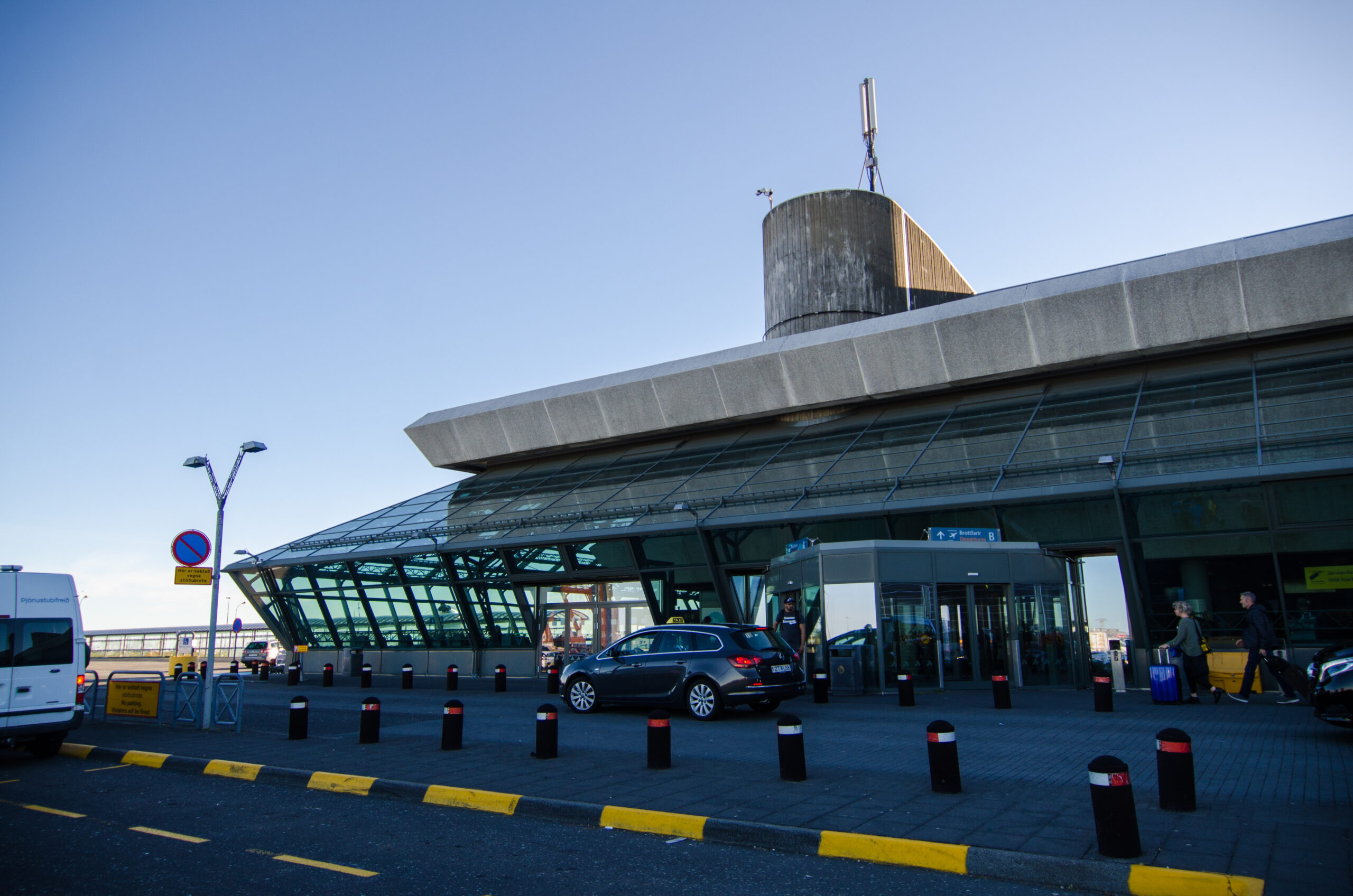 The terminal building with large windows and cars parked outside for Keflavik airport.