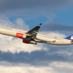 An SAS Scandinavian Airbus plane taking off from Washington airport and soaring through a cloudy blue sky.