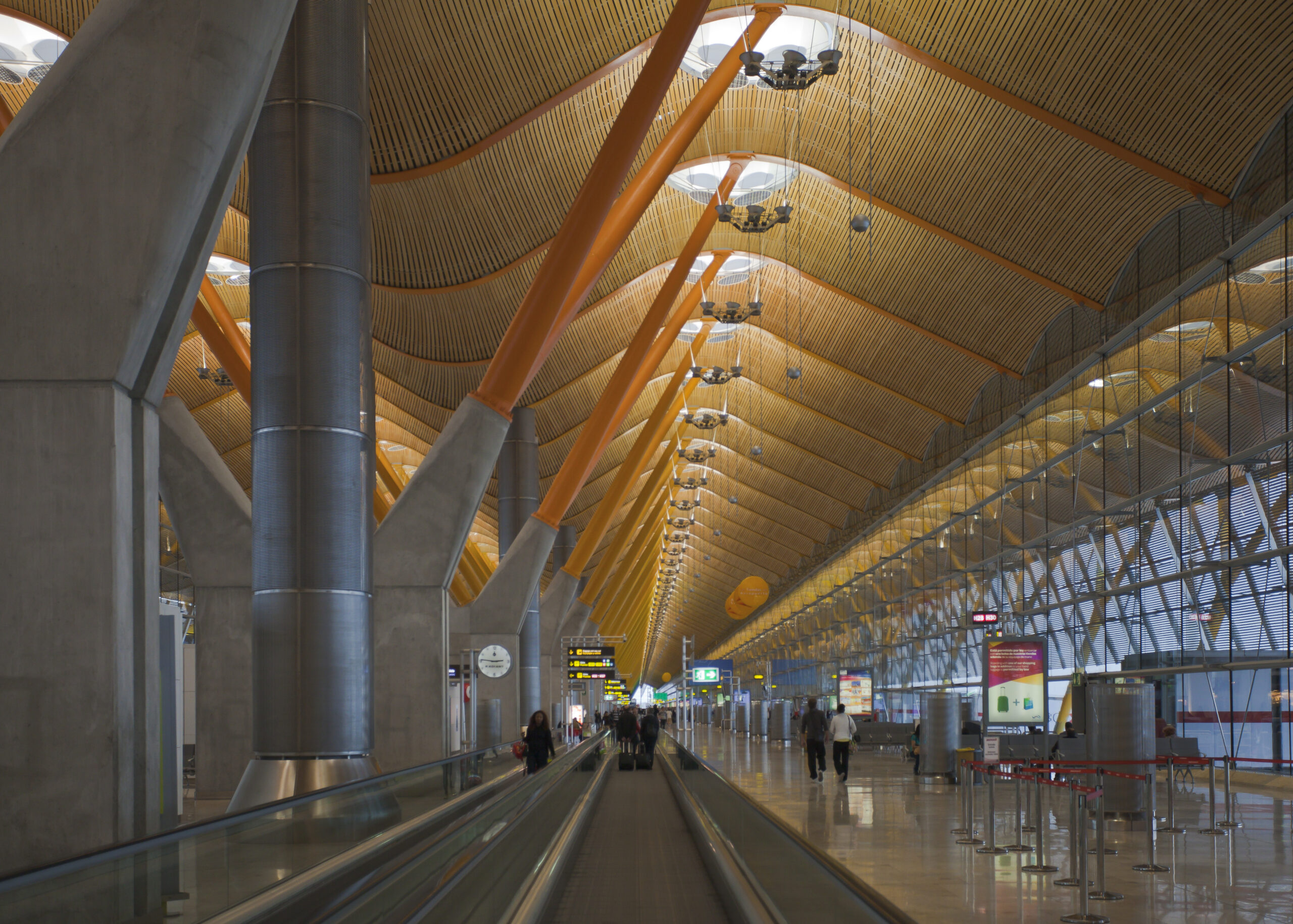 Terminal 4 of Madrid airport, with a travelator visible at the front and wooden beams lining the ceiling.