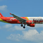 A VietJet Thailand aircraft in the sky with pictures of flight attendants on the plane body.
