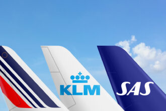The image shows the tail sections of three airplanes from different airlines against a clear blue sky. From left to right, the tails belong to Air France, KLM Royal Dutch Airlines, and Scandinavian Airlines (SAS). The Air France tail features a design with blue and red stripes and a small circle of yellow stars. The KLM tail is white with the airline's blue logo, which includes a crown symbol. The SAS tail is dark blue with the airline's white logo.