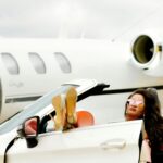 A woman in a sports car in front of a private jet.