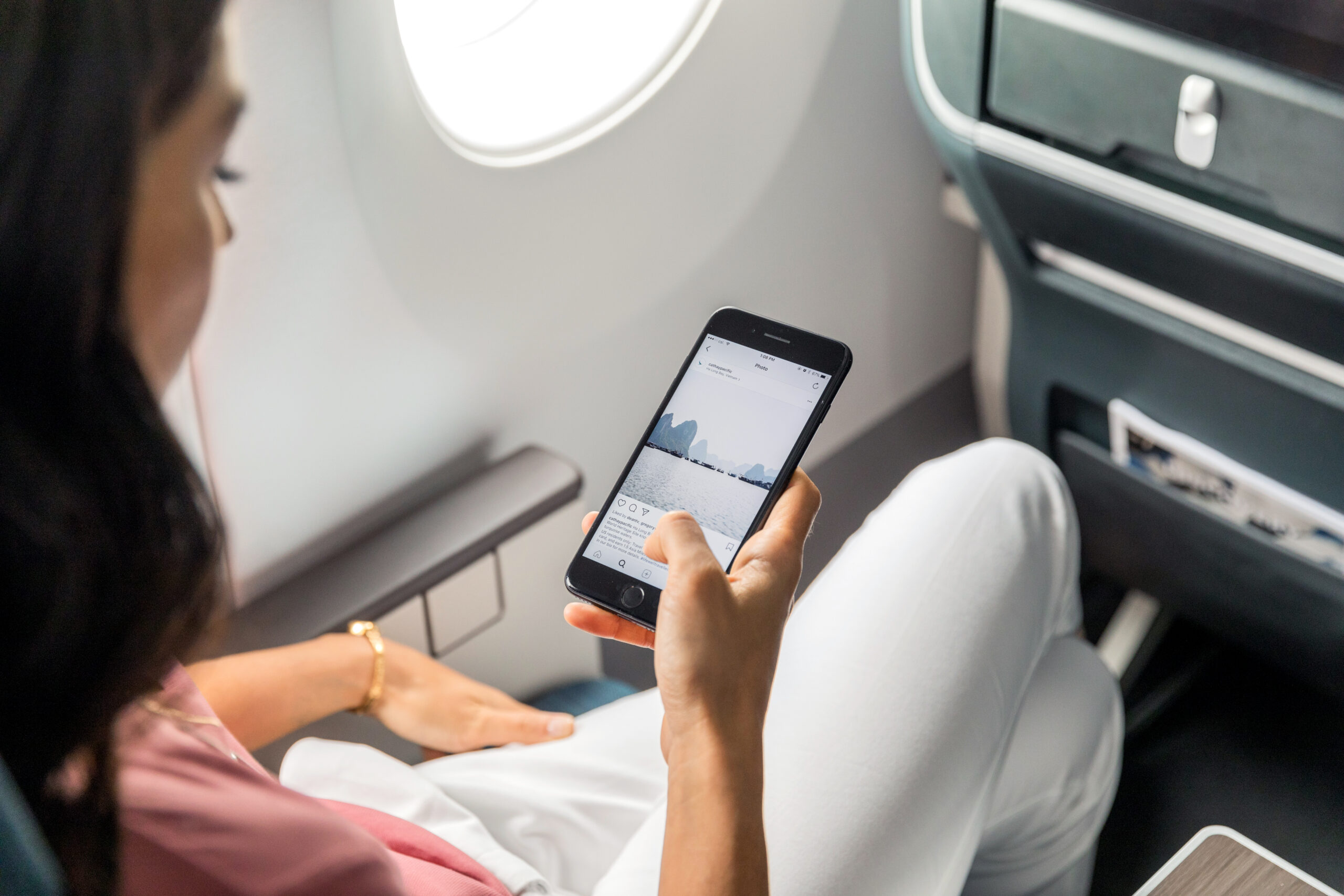 A woman scrolling on social media on a Cathay Pacific flight.