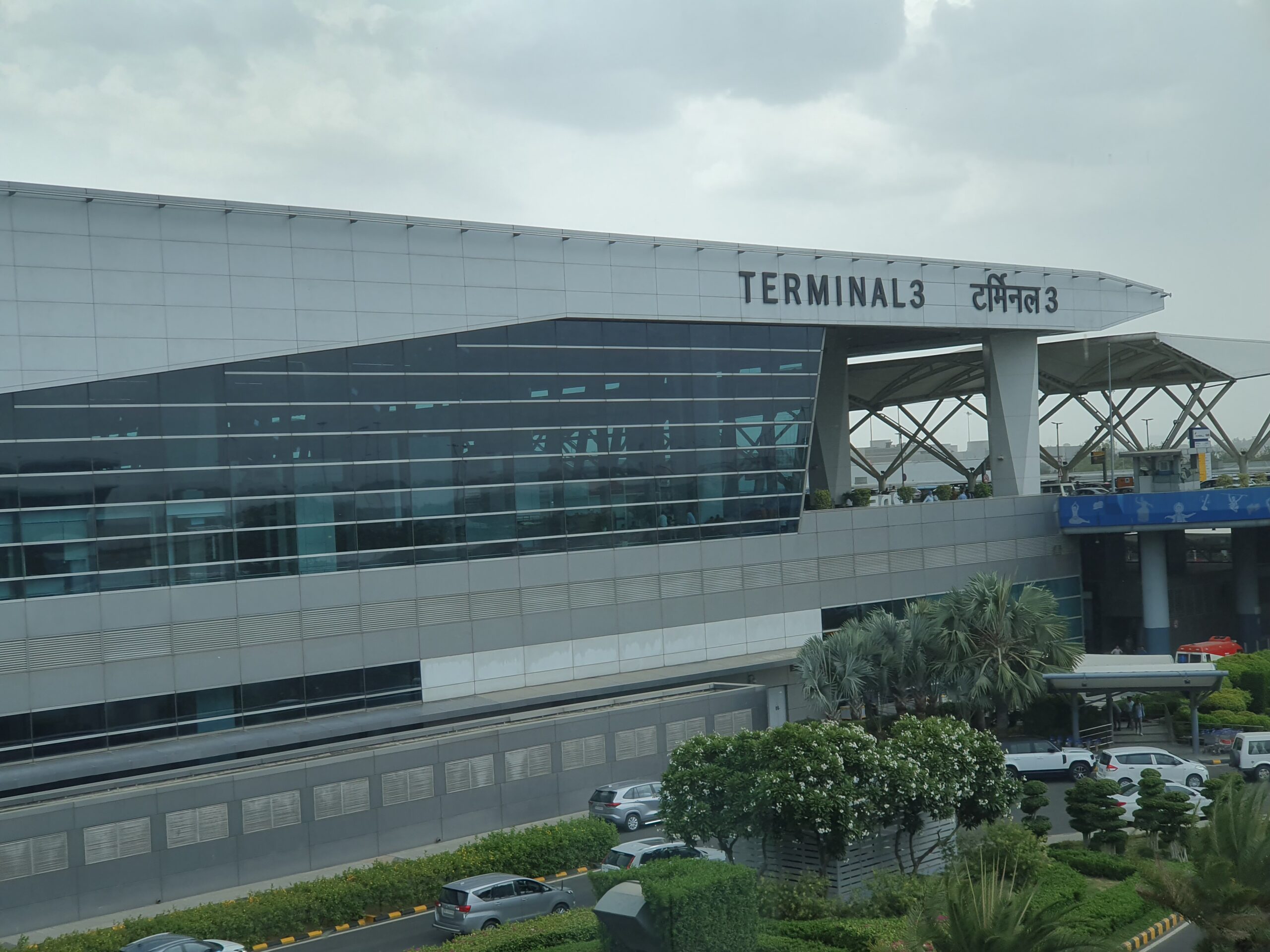 The outside of Delhi Airport terminal 3, with a sign labelling it as Terminal 3 in English and Hindi.
