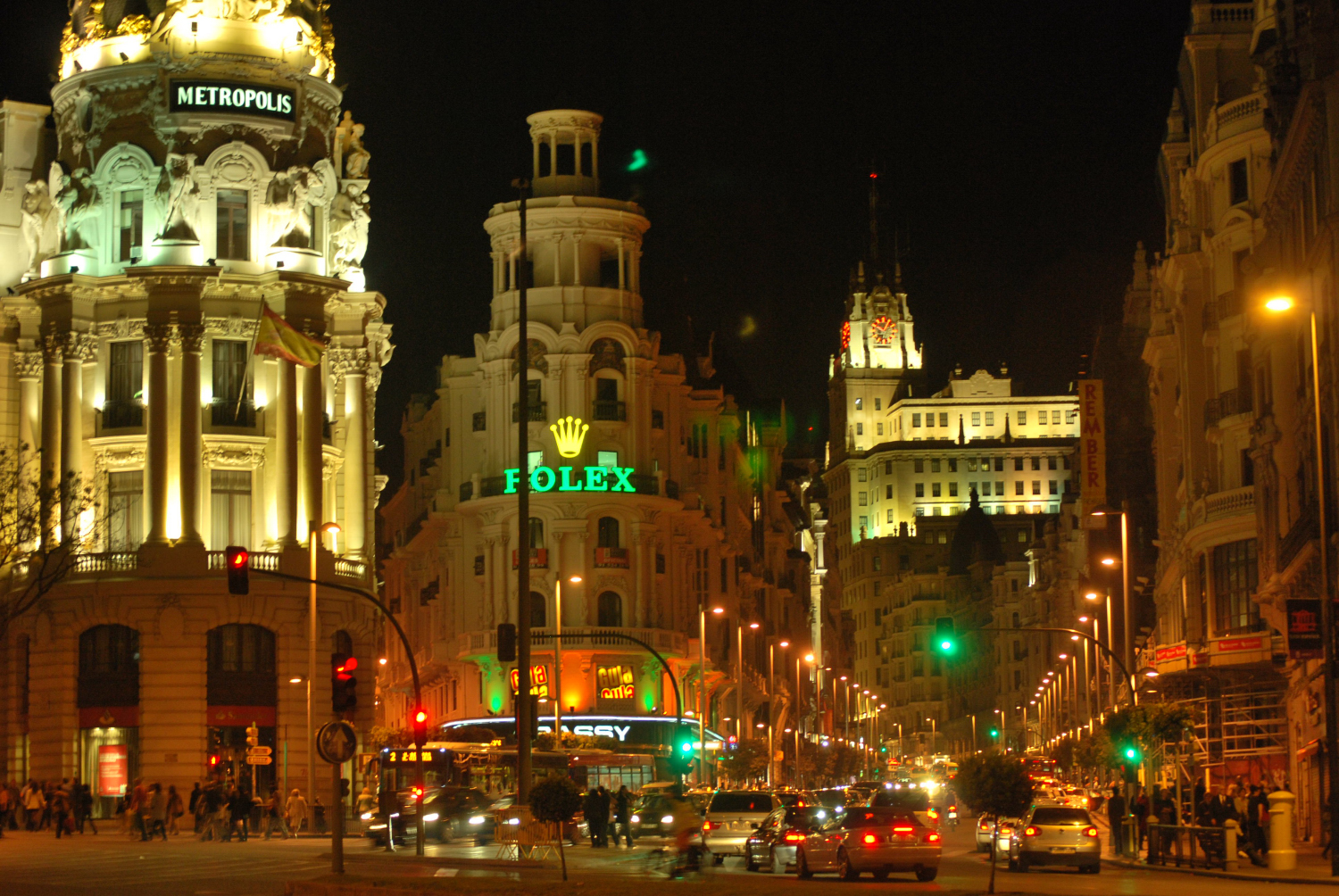 A nighttime view of downtown Madrid, with signs for Rolex and Metropolis visible.