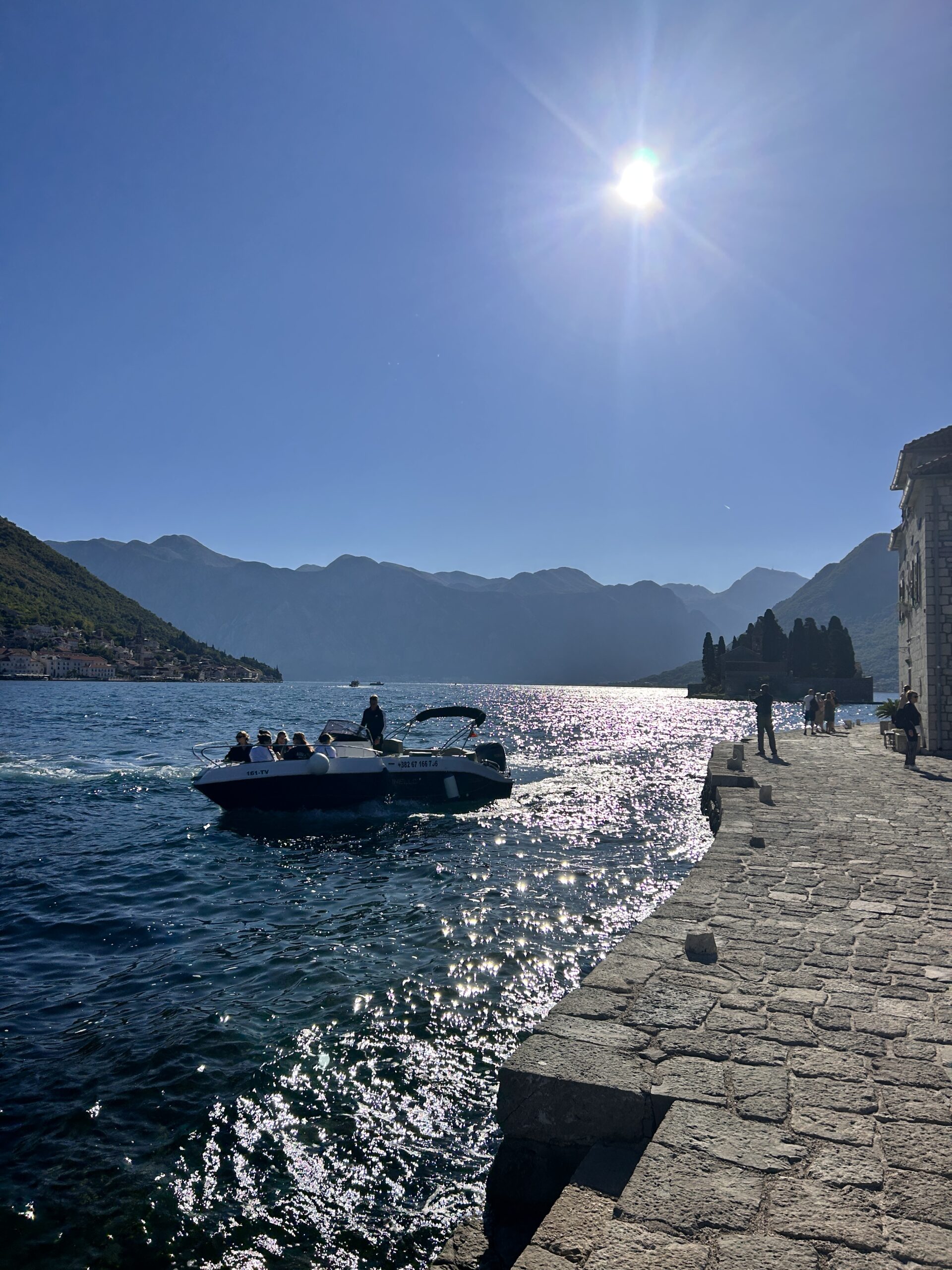 Boat on the Bay of Kotor under bright sun, captured, a highlight for Montenegro travel and Montenegro tourism, accessible via Montenegro flights to Tivat and Podgorica.