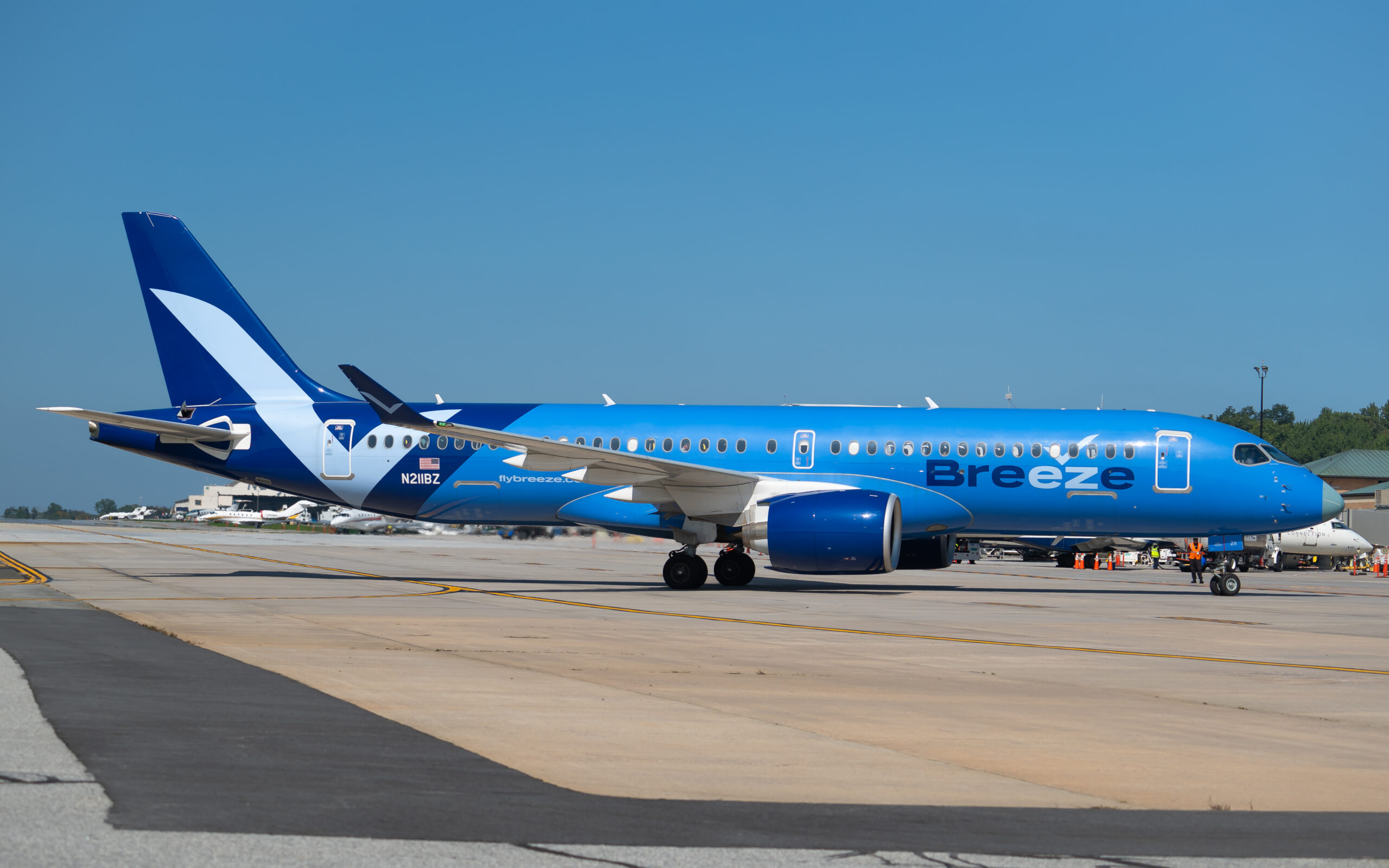 Breeze Airways Airbus A220-371 (N211BZ) taxiing to the main terminal at Westchester County Airport, illustrating the airline’s Airbus A220 fleet expansion and ongoing Breeze Airways A220 fleet growth serving underserved U.S. routes.