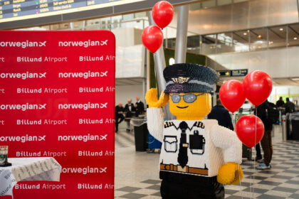 A LEGO figure next to a Billund Airport and Norwegian signboard.