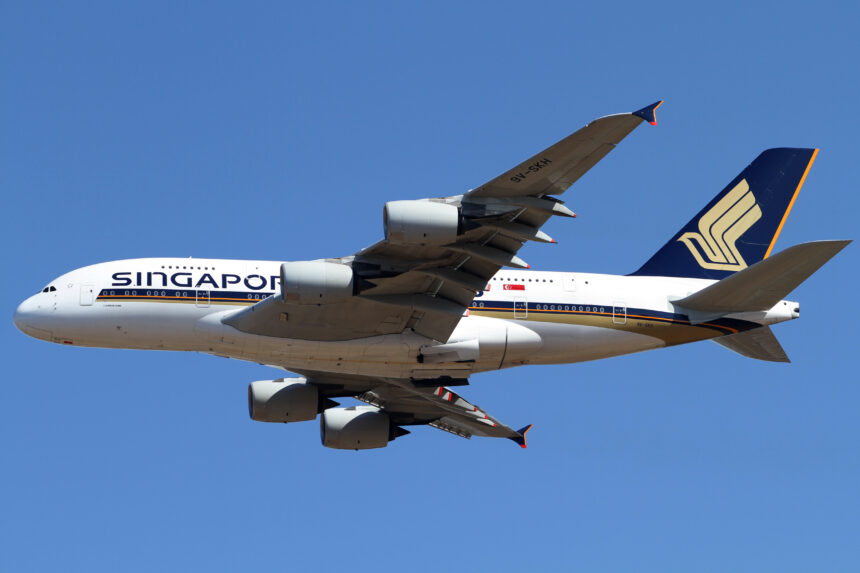 A Singapore Airlines plane flying high above the ground with a blue sky in the background.