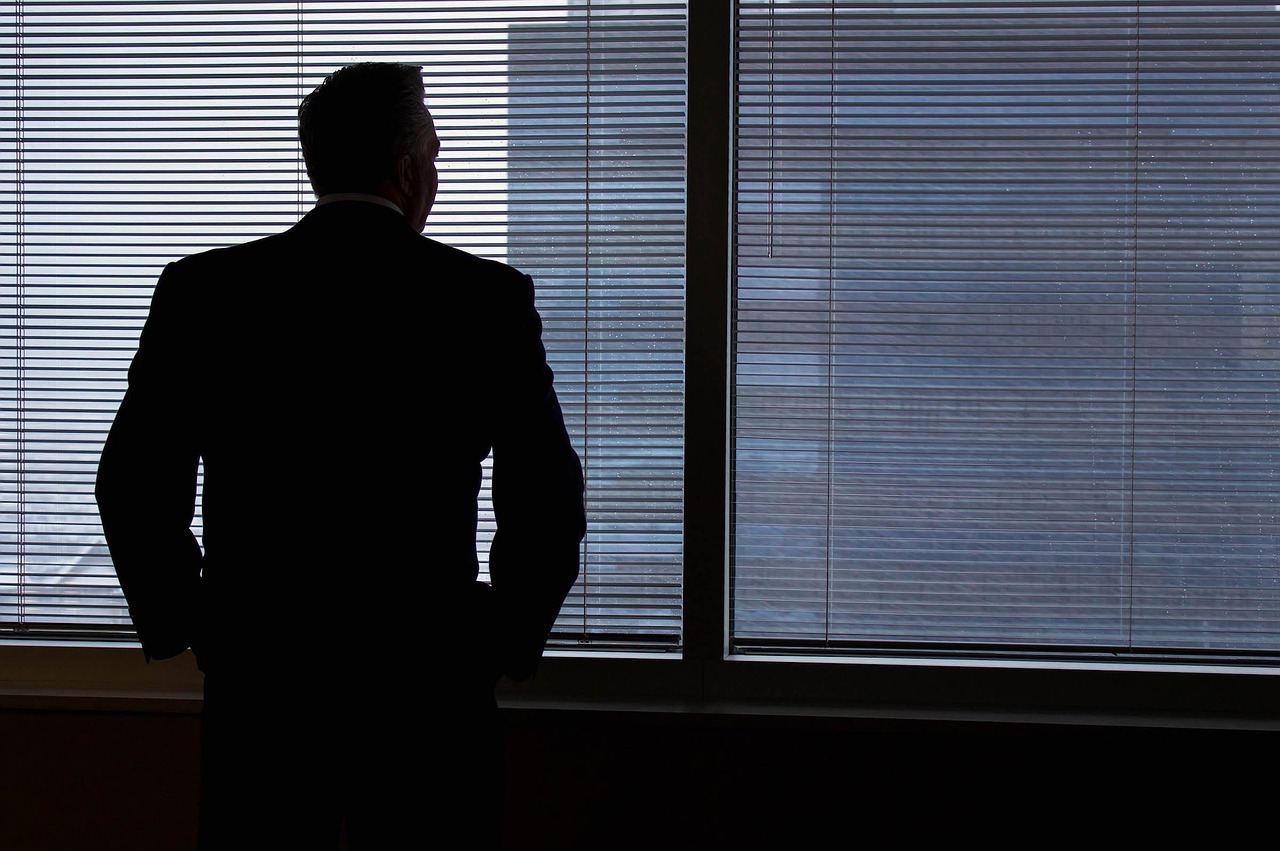 Silhouette of a business traveler standing by an office window, reflecting on business aviation growth 2025 and changing corporate travel trends.