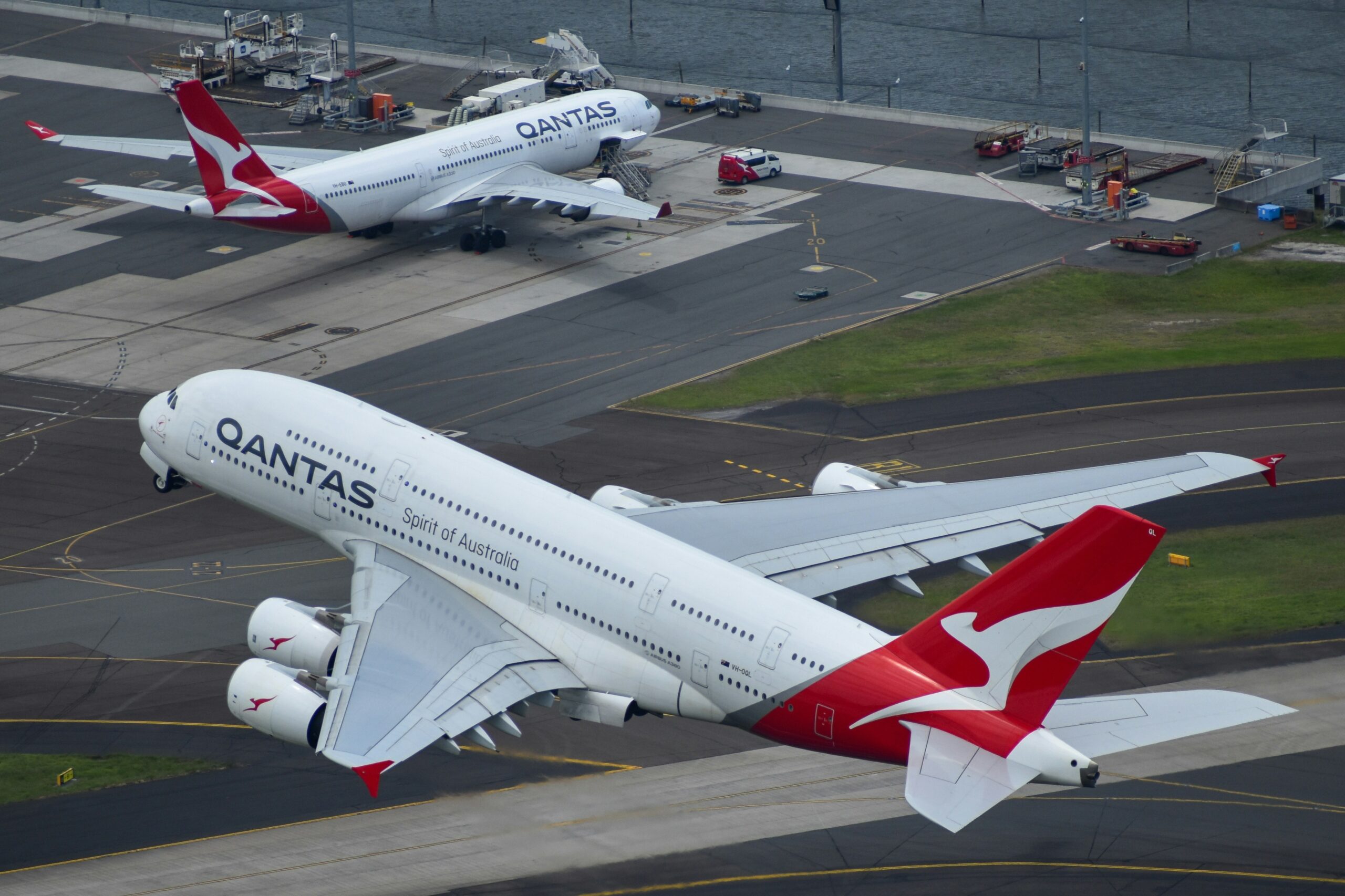 Qantas flight set to take off, one aircraft on the tarmac, another mid-air.
