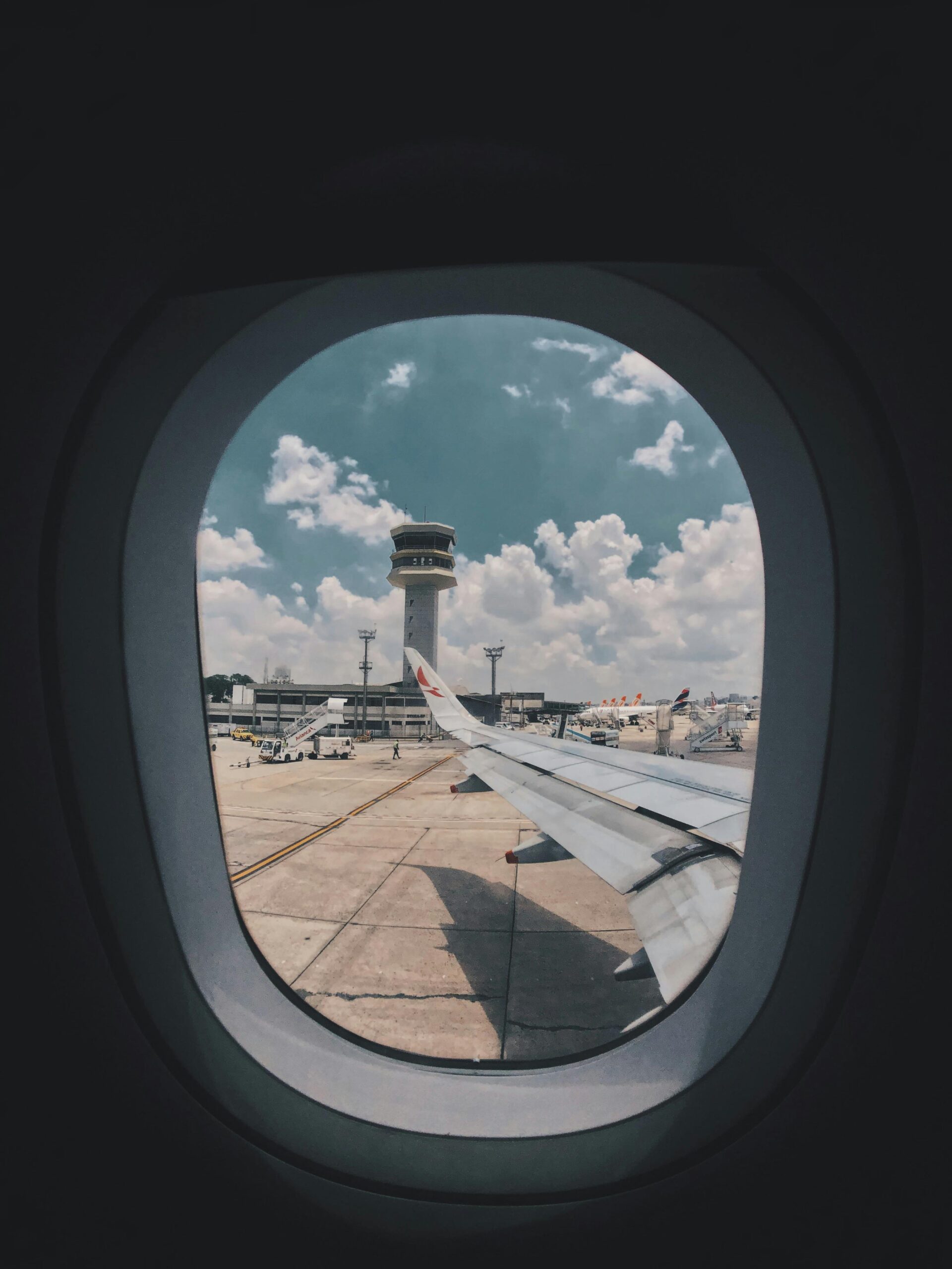 Aircraft wing and ATC tower seen from inside through a window