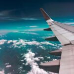 Wing of an aircraft in the sky with some white fluffy clouds in the background