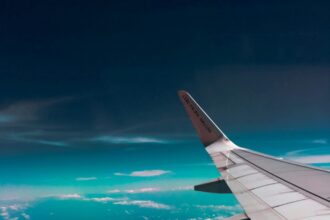 Wing of an aircraft in the sky with some white fluffy clouds in the background