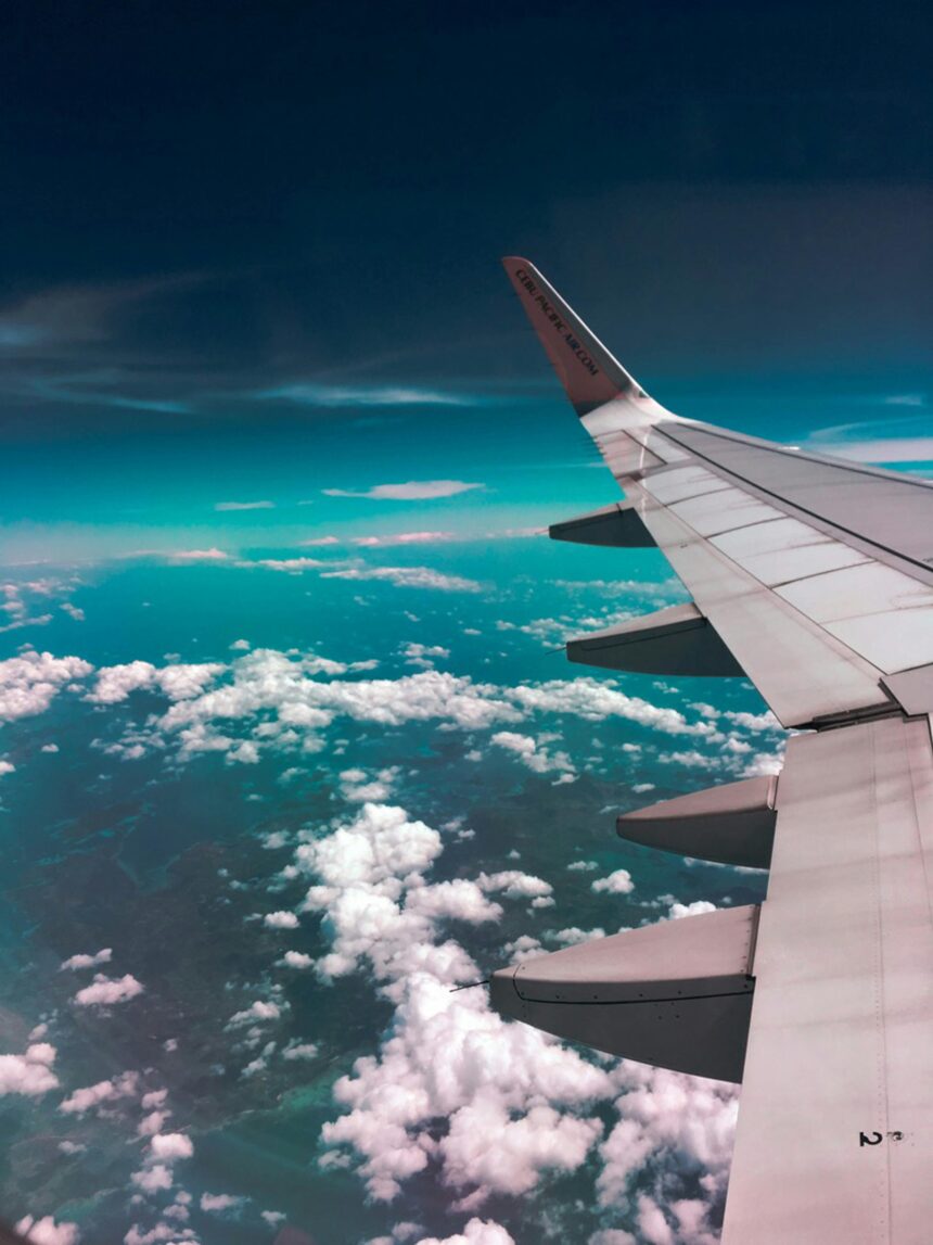 Wing of an aircraft in the sky with some white fluffy clouds in the background
