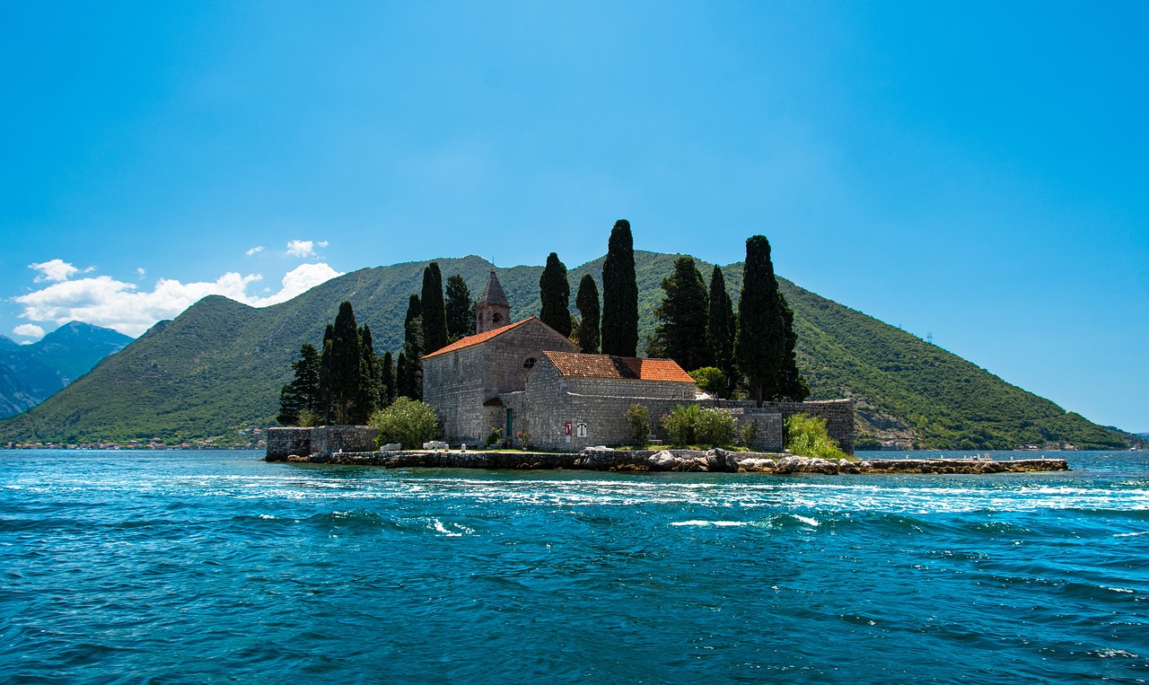 Island church surrounded by cypress trees in the Bay of Kotor, one of the best places to visit in Montenegro, easily reached via Montenegro flights to Tivat and Podgorica.