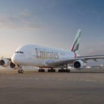 An Emirates plane grounded with the Dubai Skyline in the background