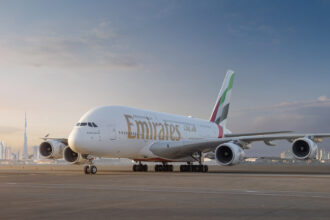 An Emirates plane grounded with the Dubai Skyline in the background