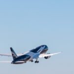 A Lufthansa plane with special livery takes off into a blue sky.