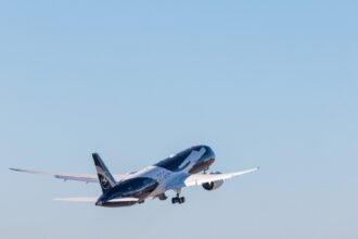 A Lufthansa plane with special livery takes off into a blue sky.