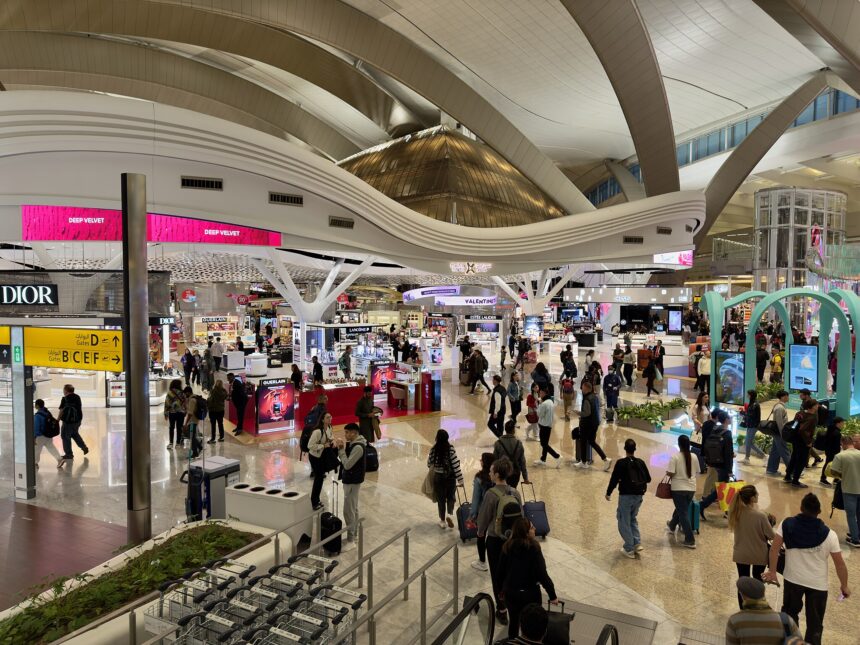 The terminal of Zayed International Airport, Abu Dhabi, with many people and duty free shops spread across the hall.