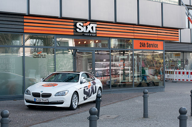 Photograph of a SIXT service shop with one SIXT logo cladded car out front.