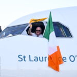 Aer Lingus pilot waves from cockpit window beside Irish flag on aircraft St Laurence O’Toole, symbolising Aer Lingus pilots during ongoing Aer Lingus industrial relations and pilot dispute.